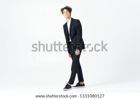 Cute curly guy in a full-length suit office worker light background