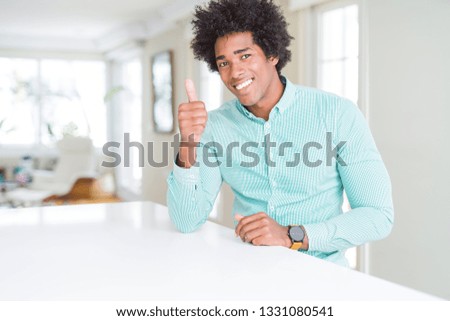 African American business man wearing elegant shirt doing happy thumbs up gesture with hand. Approving expression looking at the camera with showing success.