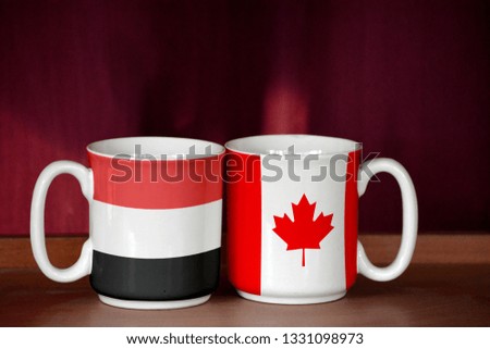 Canada and Yemen flag on two cups with blurry background