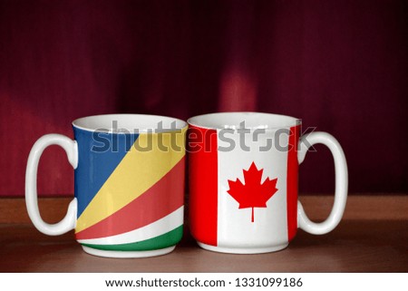 Canada and Seychelles flag on two cups with blurry background