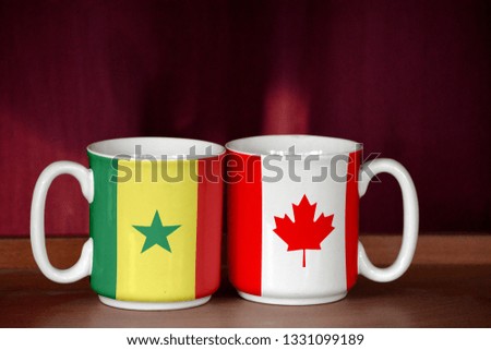 Canada and Senegal flag on two cups with blurry background