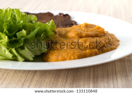 Chestnut-carrot-pumpkin mashed mix with green salad and a beef steak on the white plate