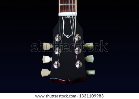 Headstock, machine head tuners and nut of a new electric guitar on a black background