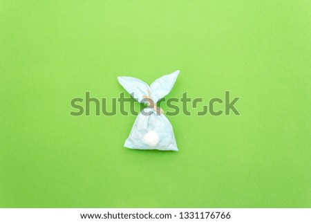 Easter bunny paper gift egg wrapping DIY idea on colorful background. Minimal easter concept, flat lay, copy space