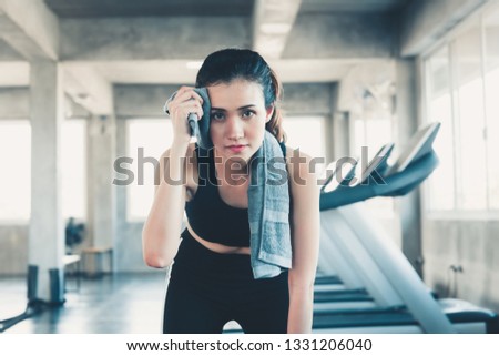 Beautiful Athletic Woman is Wiping Sweat With Towel in Gym, Portrait of Pretty girl in Sportswear is Exercising in Fitness Club. Sport Lifestyle and Healthy Concept.