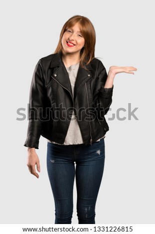 Young redhead woman holding copyspace imaginary on the palm to insert an ad over isolated grey background