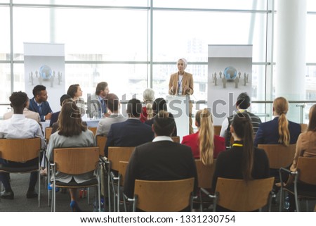 Front view of young mixed race female speaker speaking in a business seminar in modern office building