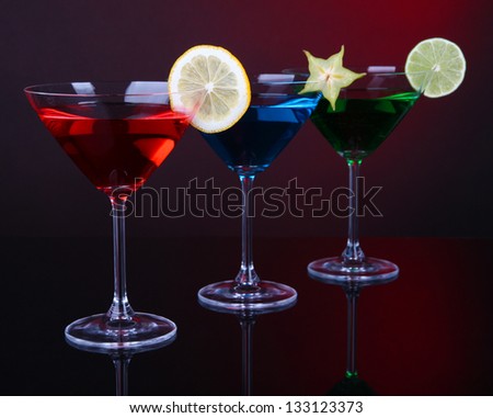 Alcoholic cocktails in martini glasses on dark red background