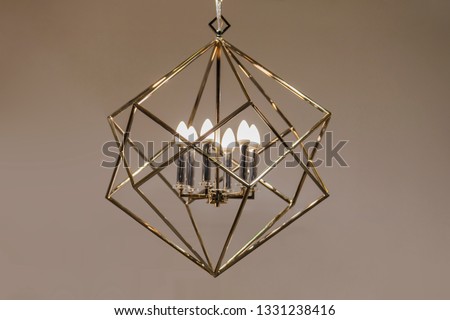 Polygonal chandelier, gold, brass, different shapes of a triangle, inside lamp there are candles. Fashion design chandeliers.
