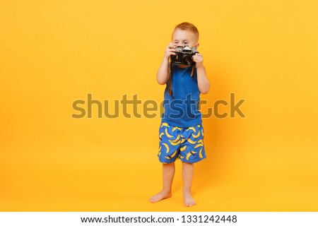 Kid boy 3-4 years old in blue beach summer clothes hold retro camera isolated on bright yellow orange wall background children studio portrait. People childhood lifestyle concept Mock up copy space