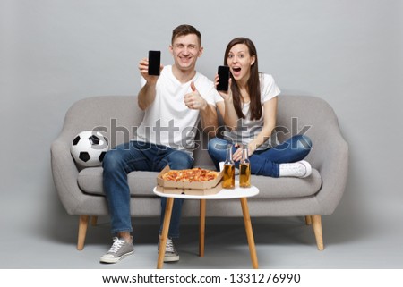 Fun couple woman man football fans cheer up support favorite team holding mobile phone with blank empty screen isolated on grey wall background. People emotions sport family leisure lifestyle concept