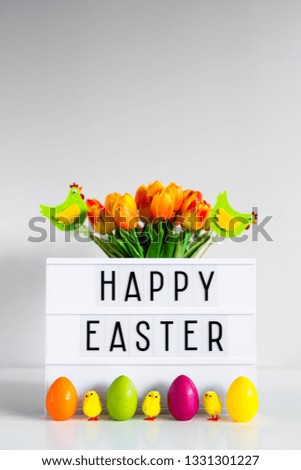 close up of vintage lightbox with happy Easter greetings, flowers, colorful eggs, decorative chicks and copy space over wall