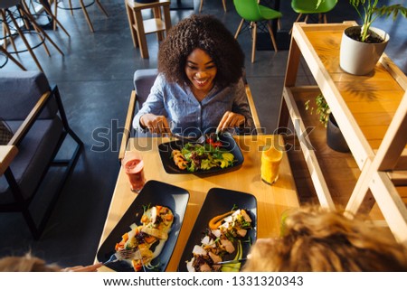 African american woman eating in cafe or restaurant with friends