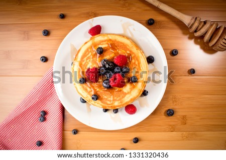American pancakes with blueberries and raspberry, over wooden surface - top view Royalty-Free Stock Photo #1331320436