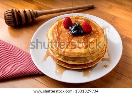 blueberry pancakes with honey, bamboo background, and utensils - hotcakes Royalty-Free Stock Photo #1331329934