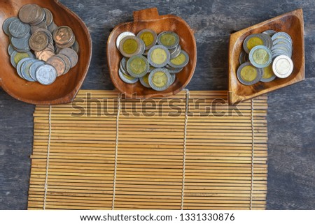 Coins placed in wooden cups on a wooden background for business