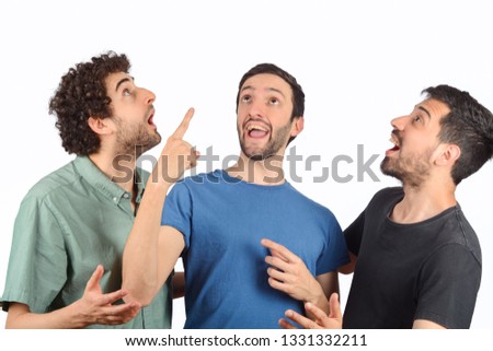 Portrait of three friends with shocked expression and pointing up.