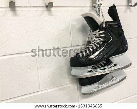 Hockey skates hanging in locker room with white brick background and copy space 