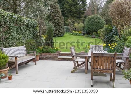Wooden bench, table and chairs on a patio in a London suburban garden