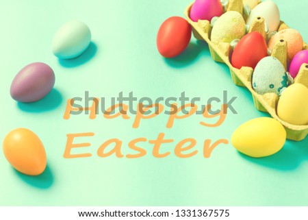 Bright Easter eggs lie in a box on a blue background. Inscription happy easter. Space for text. Easter ideas. Toned image.