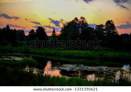 Beautiful summer landscape with sunrise in the morning on the river "Bobr", Belarusian nature. Colorful misty sunrise on a small river. Cut away thick green grass and trees.