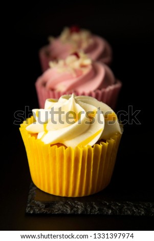 Pink and yellow cupcakes against a black background, birthday or party cupcakes. Party sweet food, desserts. Copy space.