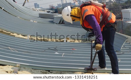 construction worker wearing harness helmet sunglass and sun protection mask to metal sheet in stalltion on high places Royalty-Free Stock Photo #1331418251