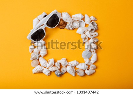 Frame from seashells with sunglasses on orange background. Summer vacation concept. Sea holidays Memories album