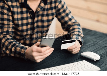 Cropped picture of man with credit card white pattern and phone