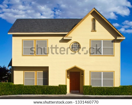 A real life yellow doll house with a red door and blue sky