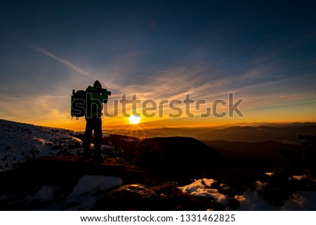 Red sunset and the silhoute of  photographer enthusiast stay on cliff and thinking..