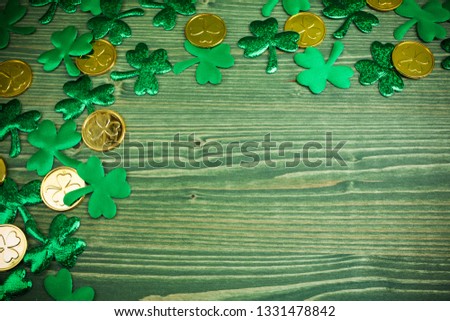 St Patricks Day corner border of shamrocks and gold coins on green wood background