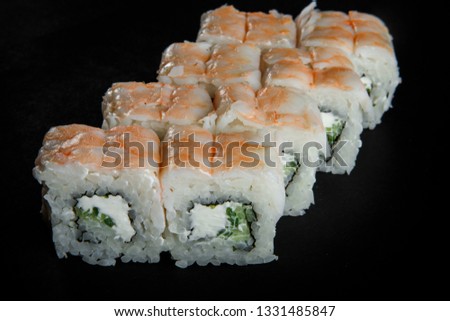 philadelphia roll sushi with cucumber, cream cheese and tiger shrimp on top served on black background