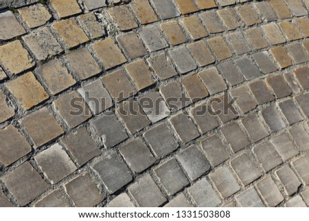 Close up perspective view of a sidewalk made of cobblestones. Pattern of grey brown blocks. Abstract picture surface with curving lines. 
