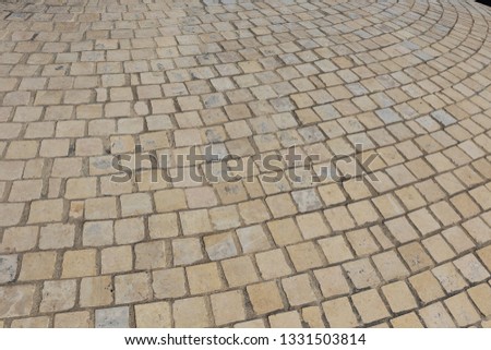 Close up perspective view of a sidewalk made of cobblestones. Pattern of grey brown blocks. Abstract picture surface with curving lines. 