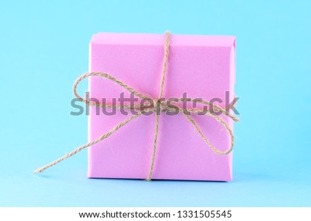 Pink gift box tied with string on a bright blue background, minimalism, parcel, place for text.
