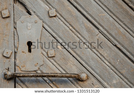 texture of an old wooden door. shabby paint. Closed door. Keyhole and door handle close-up. There is an old iron lock hinges.
