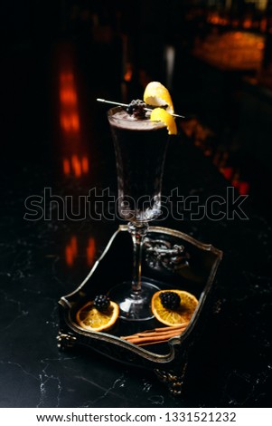 Elegant black cocktail. Close up cocktail shot on the dark bar on dark background