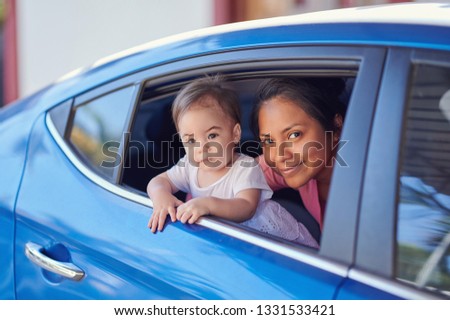 Family vacation theme. Young woman with kid looking out from car window