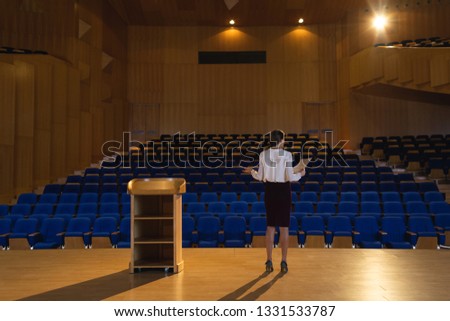 Rear view of blonde Caucasian businesswoman practicing and learning script while standing in the auditorium Royalty-Free Stock Photo #1331533787