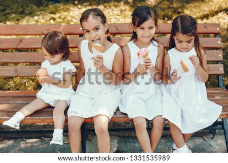 Children sitting on a bench. Family in a summer park. Cute little girls with an ice cream