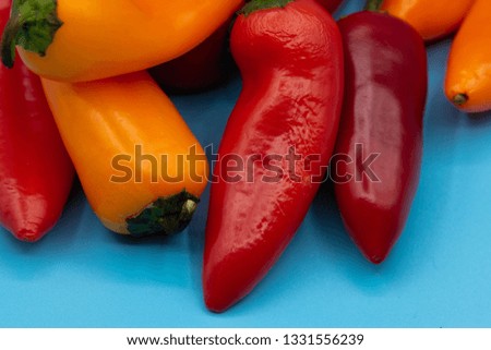 Orange and red peppers arranged on a light blue background. 