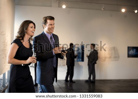Business colleagues attend an art gallery opening.