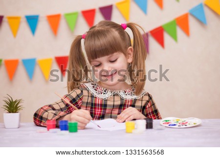 Child making homemade greeting card. Little girl paints heart on homemade greeting card as gift for Mother Day. Traditional play concept. Arts and crafts concept