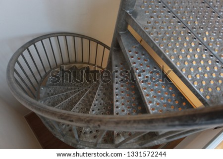 horizontal photography of silver metal spiral stars going down, by a white wall, indoors