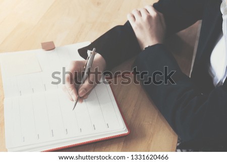 Close up. Businesswoman is writing notes and planning her schedule.