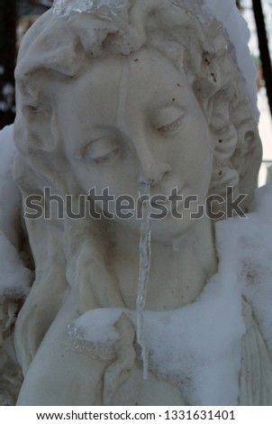 Photo of the sculpture of a female figure with an icicle resembling snot from the nose.