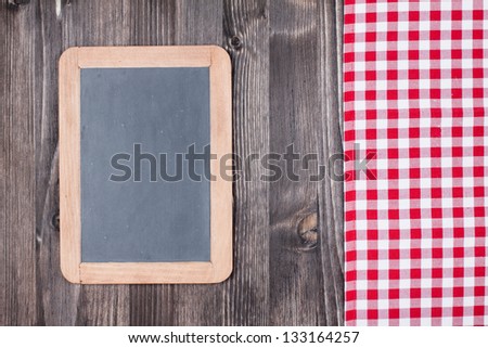 White and red tablecloth, black board on wooden table background