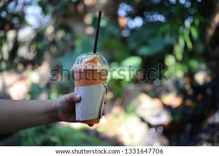 Woman hand holding a glass of cold milk tea Natural background