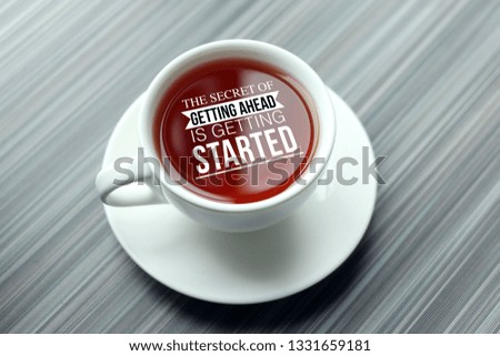 Inspirational success quotes writing on top view hot tea on wooden table. The secret of getting ahead is getting started 